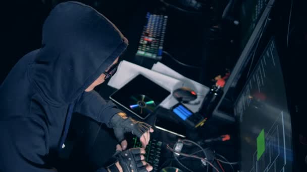 Hacker en una sudadera con capucha está operando computadoras — Vídeo de stock