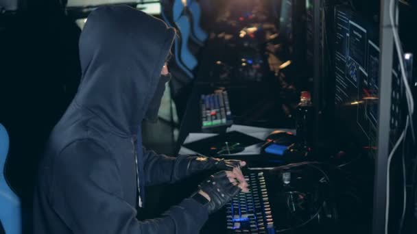 Vista lateral de un hacker disfrazado trabajando con computadoras — Vídeo de stock