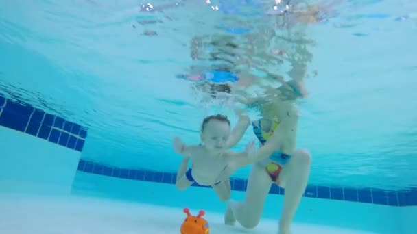 Μωρό παίρνει μέχρι ένα παιχνίδι από το κάτω μέρος της πισίνας — Αρχείο Βίντεο