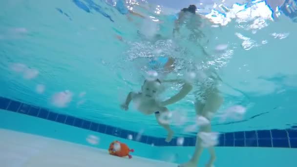 Moeder van de kinderen helpt hem om een speeltje van de bodem van het zwembad — Stockvideo