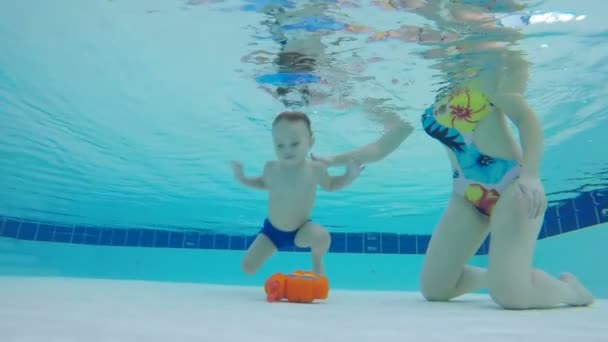 Pequeño niño está levantando un juguete bajo el agua con su ayuda de las madres — Vídeos de Stock