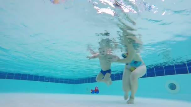 Niño está buceando bajo el agua bajo el control de sus madres — Vídeo de stock