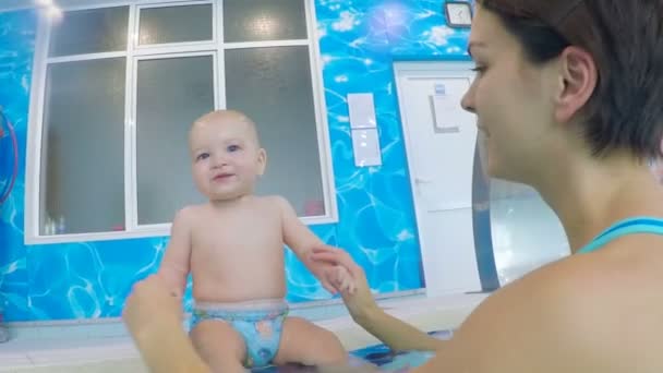 Una mujer está jugando con un bebé en el tablero de la piscina. — Vídeo de stock