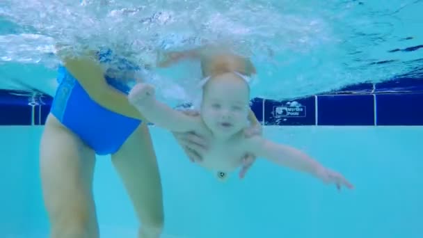 El bebé está nadando bajo el agua con la ayuda de las mujeres — Vídeos de Stock