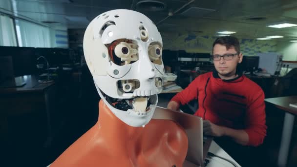 Vrouwelijke specialist is het aanpassen van een mens-achtig masker op het gezicht van een robots — Stockvideo