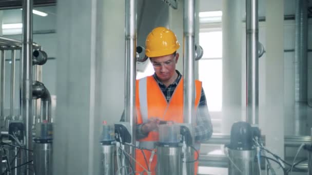 Male technician regulates pressure in brewing equipment — Stock Video
