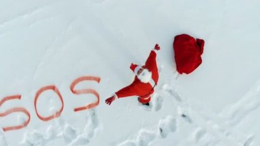 Onun yanında yazılı bir Sos işareti ile karda Noel Baba