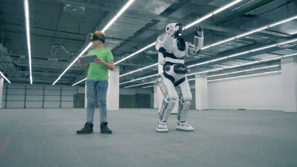 戴 vr 眼镜的男孩, 带着平板电脑, 机器人在他身边移动 — 图库视频影像
