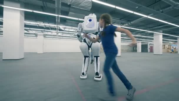 Дівчинка і хлопчик граються з роботом і бігають навколо нього — стокове відео