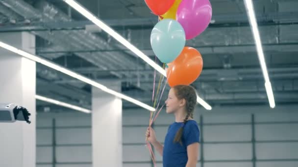 Маленька дівчинка дає повітряні кулі людському кіборду — стокове відео