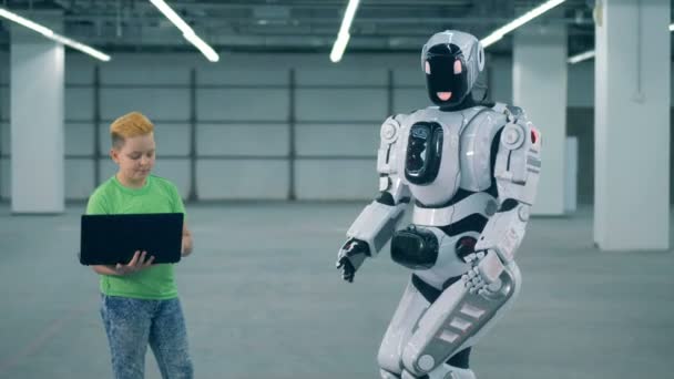 Robot wordt gecontroleerd door een jongen met een laptop — Stockvideo