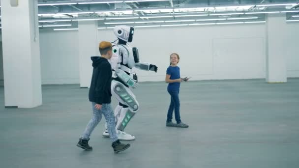 Duas crianças estão controlando o processo de caminhada de um cyborg semelhante ao humano — Vídeo de Stock