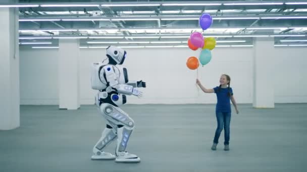 A girl with balloons is dancing and a manlike robot is coming towards her — Stock Video