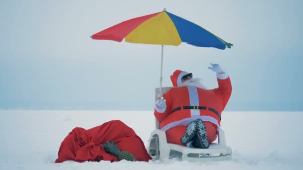 Claus bebe champanhe em uma cadeira de praia ao ar livre, de perto . — Vídeo de Stock