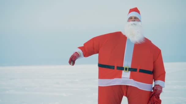 Santa i en kostym promenader, hålla en väska med presenterar. — Stockvideo