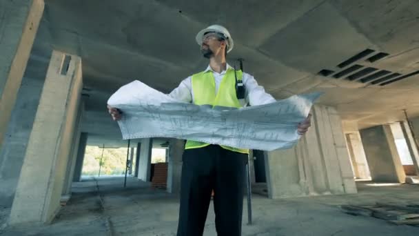 L'ingegnere guarda il layout di un edificio, da vicino . — Video Stock