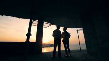 İnşaatçılar cityscape bir gün batımı arka, geri görünüm bak.