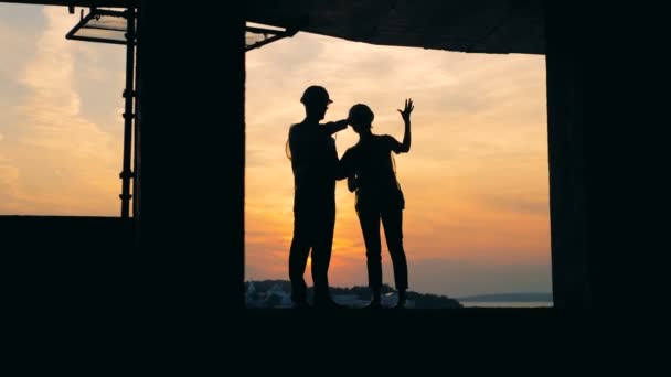 Homem e mulher trabalham em um edifício em um fundo por do sol, close-up . — Vídeo de Stock