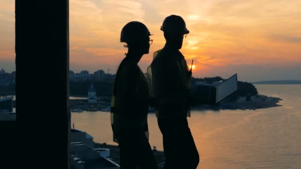 Los constructores trabajan con una computadora portátil en un fondo de puesta de sol, de cerca . — Vídeo de stock