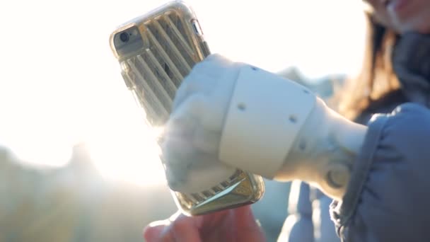 Close up van een mobiele telefoon wordt geëxploiteerd door een meisje met een robotic hand — Stockvideo