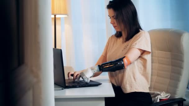 Laptop is getting operated by a young woman with a bionic arm — Stock Video