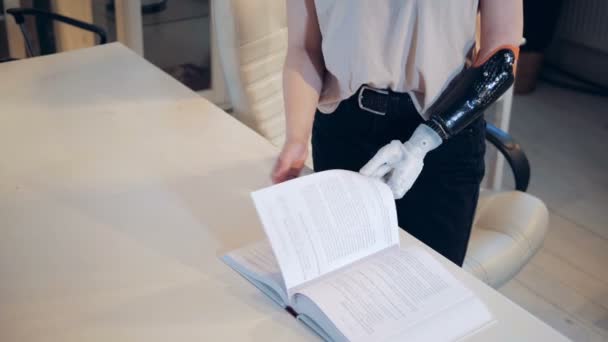 Una mujer con un brazo biónico está pasando páginas de un libro — Vídeos de Stock