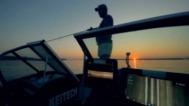 Bir adam balık günbatımı bir arka planda yakalar, yakın çekim.