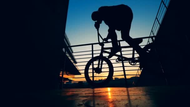 Ein Fahrer springt auf einem Fahrrad auf einem Sonnenuntergang Hintergrund, Zeitlupe. — Stockvideo