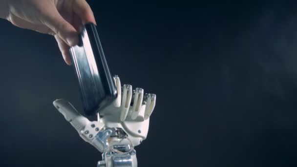 Bioniczna ręka trzyma telefon komórkowy, z bliska. — Wideo stockowe