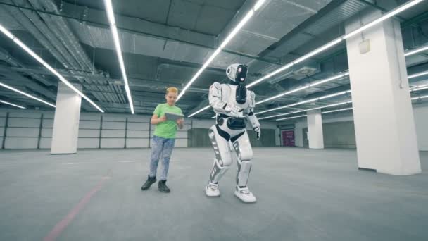 Un niño ve a un robot caminando, de cerca . — Vídeos de Stock