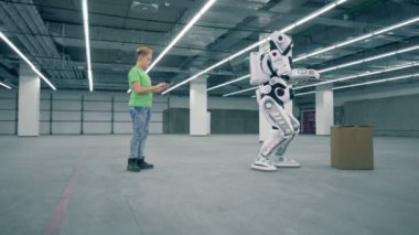 Bir kutu alır iken bir çocuk robot kontrol eder. Fütüristik insansı robot.
