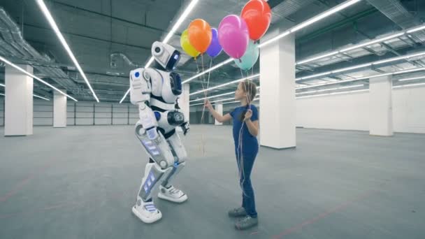 Ein Mädchen gibt einem Roboter farbige Luftballons aus nächster Nähe. — Stockvideo