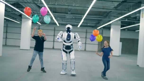 Android та діти танцюють з повітряними кулями. Сучасний кіборг з дітьми — стокове відео
