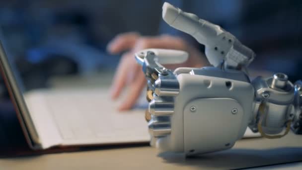 Una persona con mano robotica che lavora con un computer portatile, da vicino . — Video Stock