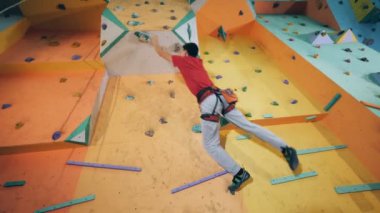 Bir adam elinde bir rock, alt görünümü bir duvarda asılı.