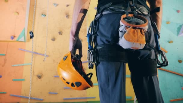 Чоловік з обладнанням для скелелазіння стоїть біля стіни, крупним планом . — стокове відео