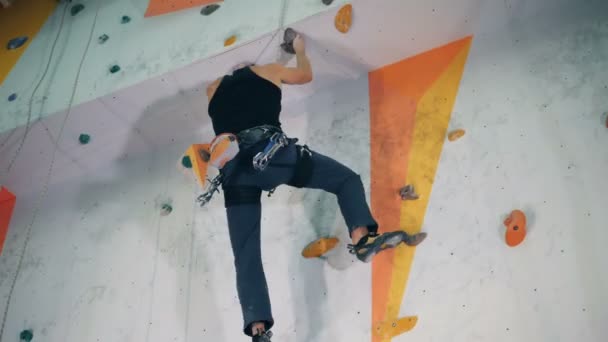 En man klättrar på en hög mur, underifrån. — Stockvideo