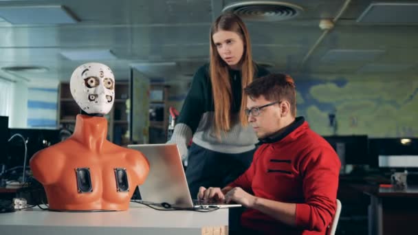 Мужчина и женщина работают с компьютером, управляя роботом, крупным планом . — стоковое видео