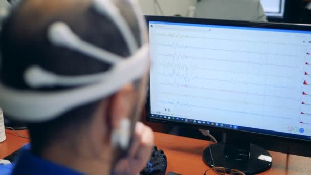 Un trabajador revisa su cerebro mientras usa sensores en una cabeza, vista trasera . — Vídeos de Stock