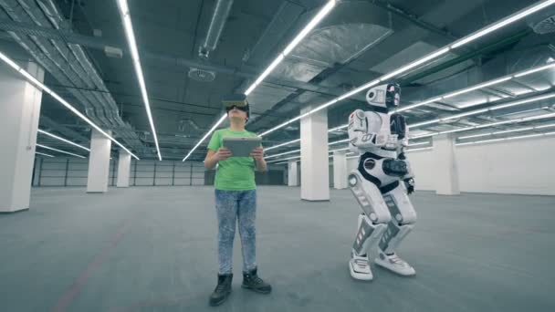 Unidad de almacenamiento vacía con un niño en gafas VR y un robot en movimiento — Vídeo de stock