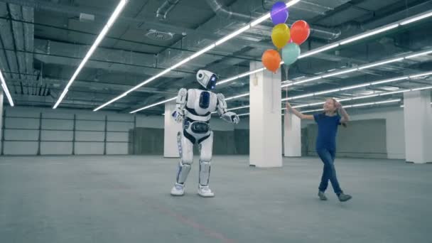 Tienermeisje is dansen met ballonnen en wandelen met een mens-achtig droid — Stockvideo