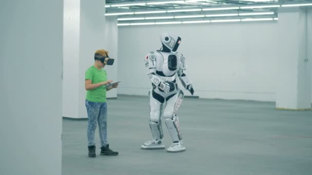 Um rapaz com óculos de realidade virtual está a manipular um cyborg para se mover. — Vídeo de Stock