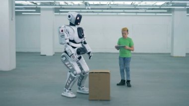 Genç çocuk bir kutusunu kaldırmak için bir robot komutları