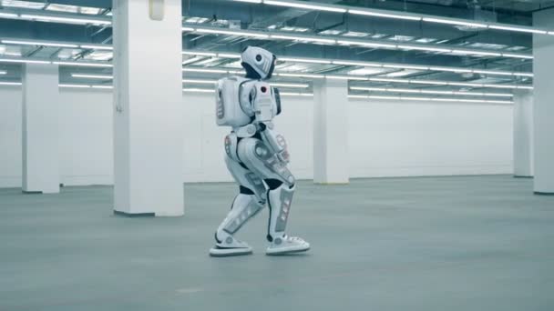 Höga människoliknande cyborg promenader längs ett tomt lager enhet — Stockvideo