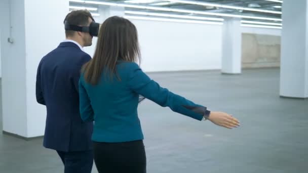 Agen properti wanita menunjukkan aula kosong kepada seorang pengusaha dengan kacamata VR. Real estate komersial . — Stok Video