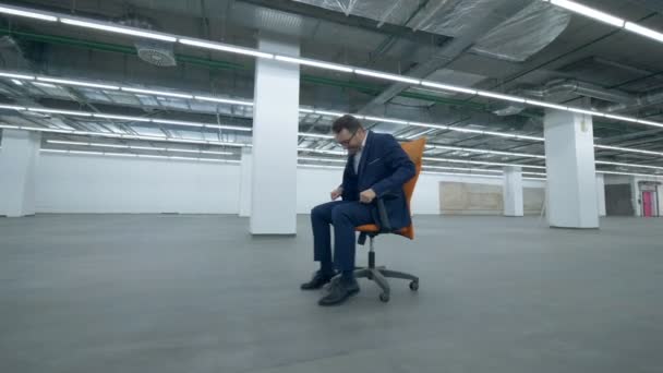 Le chef de bureau est sur une chaise roulante à travers une salle vide — Video