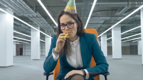 Salón vacío con una mujer cansada en traje de oficina y un sombrero de cumpleaños — Vídeo de stock