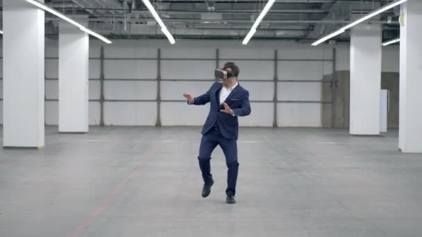 Бизнесмен в VR-очках ходит по пустому залу — стоковое видео
