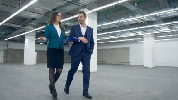 Estate broker is leading a businessman through an empty hall — Stock Video