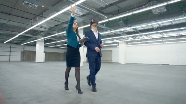 Man in de Vr-bril is via de eigenschap krijgen geleid door een dame-agent — Stockvideo
